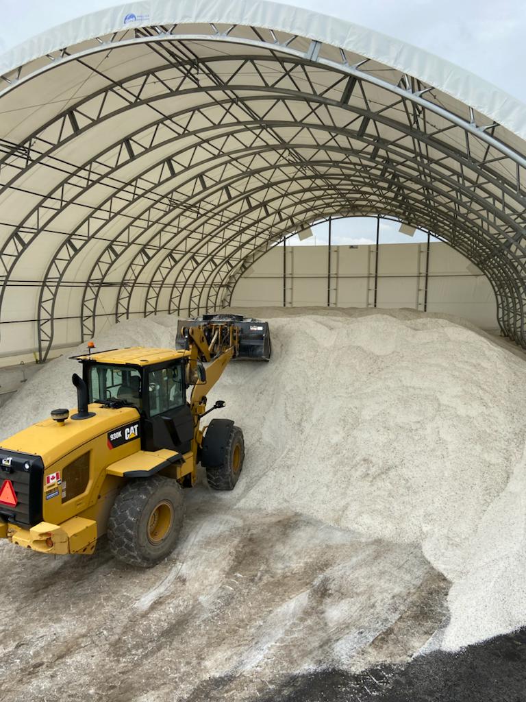 A yellow bulldozer is collecting sand inside a dom